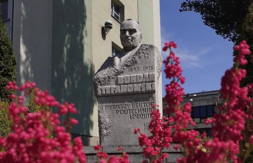 Pomnik pierwszego rektora PŁ, prof. Bohdana Stefanowskiego wśród różowych kwiatów.
