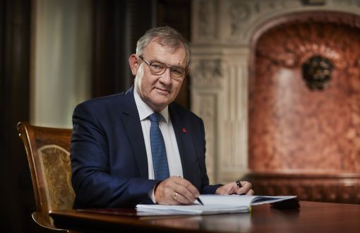 Prof. Krzysztof Jóźwik, rektor PŁ, siedzi przy biurku w swoim gabinecie i podpisuje dokumenty.