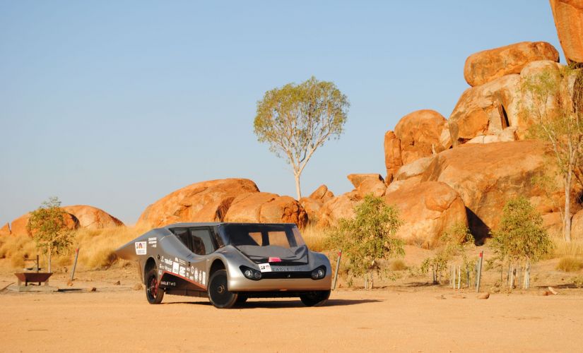 Srebrny Eagle Two - pojazd zespołu Lodz Solar Team, w australijskiej scenerii tj. na piasku, w tle skały o kolorze piasku.