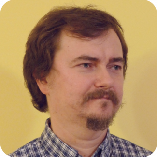 Zdjęcie portretowe: prof. Szymon Grabowski w koszuli w kratkę na żółtym tle.
