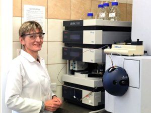 Prof. Beata Kolesińska w białym fartuchu przy maszynie laboratoryjnej.
