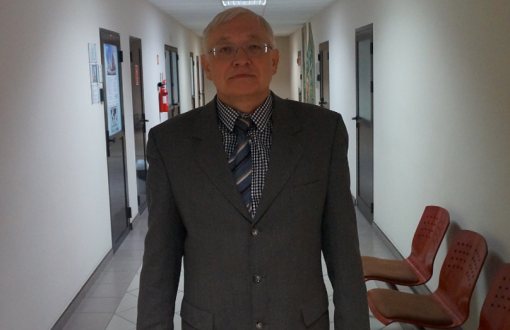 Prof. Volodymyr Mosorov w garniturze na korytarzy instytutu. Po prawej i lewej stronie drzwi do pokoi.