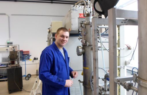 Dr Maciej Fronczak w niebieskim fartuchu w laboratorium Centrum Badań Nauk Przyrodniczych w Budapeszcie.