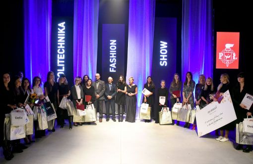Kilkanaście osób elegancko ubranych z symbolicznymi czekami i nagrodami na tle fioletowej scenografii z napisem Politechnika Fashion Show.