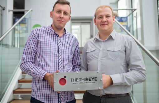 Łukasz Adamek (po lewej) i Paweł Kielanowski w jasnych koszulach trzymają w dłoniach i prezentują urządzanie z logo ThermoEye.