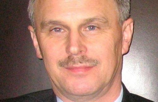 Zdjęcie portretowe: dr inż. Adam Rylski w czarnym garniturze i białej koszuli na szarym tle.