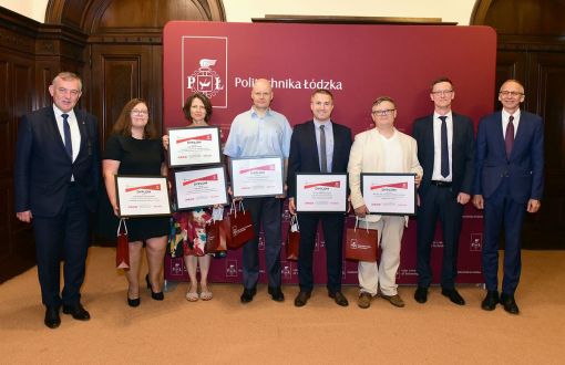 Laureaci projektu IDEA BOX 2021 nagrodzeni przez rektora PŁ, prof. K. Jóźwika stoją na tle bordowej ścianki z logo uczelni.