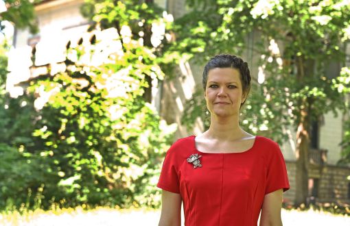 Zdjęcie portretowe: prof. Anna Fabjańska w czerwonej sukience na tle zieleni.
