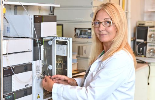prof. Grażyna Leszczyńska w białym fartuchu przy aparaturze chemicznej.
